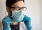 A young handsome doctor wearing glasses and a medical face mask puts on a stethoscope while preparing for a patients examination