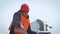 Young handsome engineer, architect, builder, businessman, wearing a helmet, in a construction vest, using the phone