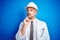 Young handsome engineer man wearing safety helmet over blue  background with hand on chin thinking about question, pensive