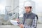 Young handsome foreman writing on clipboard at construction site