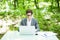 Young handsome freelance working at laptop at office table in green park. Business concept.