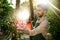 Young handsome gardener smiling, watering, taking care of flowers. Flare sunlight on background.