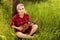 Young handsome girl sit in green grass and play on ukulele on wood background