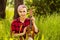 Young handsome girl sit in green grass and play on ukulele on wood background