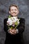 Young handsome groom smiling, holding bridal bouquet over grey background.