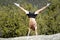 A young handsome gymnast poses a handstand on a mountain top.