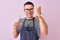 Young handsome hairdresser man wearing apron over pink isolated background annoyed and frustrated shouting with anger, crazy and