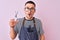 Young handsome hairdresser man wearing apron over pink isolated background scared in shock with a surprise face, afraid and