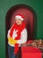 Young handsome happy man wearing Santa hat and yellow mittens on Christmas gift box in the green arch background