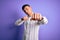 Young handsome hispanic man wearing elegant business shirt standing over purple background Punching fist to fight, aggressive and