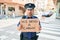 Young handsome hispanic policeman wearing police uniform with serious expression holding we need a change banner at town street
