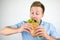 Young handsome hungry man eats fresh sandwich with salad leaf on  white background