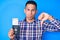 Young handsome latin man holding united states passport and boarding pass with angry face, negative sign showing dislike with