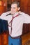 Young handsome looking man dressing up dark red modern tie in hotel room