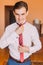 Young handsome looking man dressing up modern tie in hotel room. Close-up