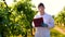 A young handsome male biologist or agronomist, working in a tablet, wearing a white coat, wearing goggles, wearing blue rubber g