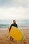 Young handsome male surfer with a surfboard is enjoying a view while walking a sandy beach at sea. Summer, vacation, ocean.