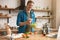 Young handsome man adding salt and spices to salad while cooking lunch standing in well-equipped modern kitchen checking recipe in