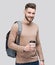 Young handsome man with backpack holding coffee cup isolated on gray background. Smiling student or businessman studio portrait