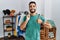 Young handsome man with beard holding shopping bags at retail shop doing happy thumbs up gesture with hand