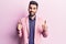 Young handsome man with beard wearing elegant jacket success sign doing positive gesture with hand, thumbs up smiling and happy