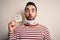 Young handsome man with beard wearing medical mask holding virus alert reminder scared in shock with a surprise face, afraid and