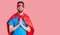 Young handsome man with beard wearing super hero costume begging and praying with hands together with hope expression on face very