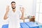 Young handsome man with beard working at pain recovery clinic showing and pointing up with fingers number nine while smiling