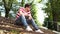 A young handsome man in casual clothes is sitting on the steps in the park and looking around.