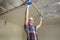 Young handsome man in casual clothing takes measurement of drywall suspended ceiling connected to metal frame on ceiling insulated