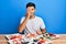 Young handsome man eating sushi sitting on the table covering one eye with hand, confident smile on face and surprise emotion