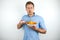 Young handsome man eats chips holds remote control on isolated white background