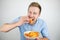 Young handsome man eats chips on isolated white background