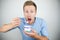 Young handsome man eats yogurt holding spoon in his hand close to his mouth on isolated white background