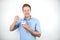 Young handsome man eats yogurt with spoon smiling on isolated white background