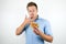 Young handsome man enjoying cheeseburger from fast food restaurant licking his fingers while eating on isolated white