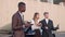 A young handsome man gives a presentation on a tablet for two businessmen, a woman and a man. Shooting near the office