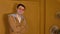 Young handsome man in glasses standing against background of brown doors in room. Portrait of stylish male looking on