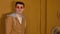 Young handsome man in glasses standing against background of brown doors in room. Portrait of stylish male looking away.