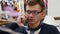 Young handsome man in glasses talking on the cellphone in shopping mall and working with laptop. Close-up