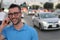 Young handsome man with glasses talking on his smart phone, traffic jam in background with copy space