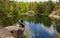 Young Handsome man in Hat On A Rock Admiring The View Of A Lake In Autumn.