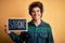 Young handsome man holding blackboard with strong word over isolated yellow background with a happy face standing and smiling with