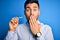 Young handsome man holding dental aligner tooth correction over blue background cover mouth with hand shocked with shame for