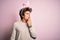 Young handsome man holding easter rabbit ears standing over isolated pink background bored yawning tired covering mouth with hand