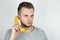 Young handsome man holding fresh banana like a smartphone near his ear on isolated white background