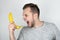 Young handsome man holding fresh banana like a smartphone screaming on isolated white background