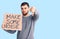 Young handsome man holding make some noise banner with angry face, negative sign showing dislike with thumbs down, rejection