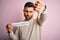 Young handsome man holding paper with self love message over pink background with angry face, negative sign showing dislike with