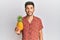 Young handsome man holding pineapple looking positive and happy standing and smiling with a confident smile showing teeth